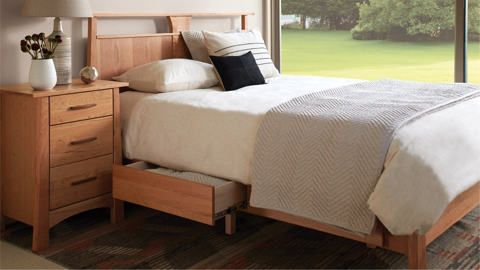 Wood platform bed with storage drawer, neutral bedding, and matching nightstand.